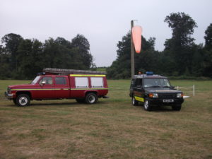 two vehicles and a windsock at a temporary helipad