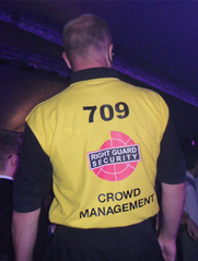 back view of a security guard wearing a branded "crowd management" t-shirt